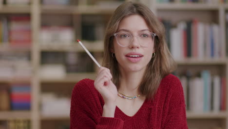 Una-Joven-Estudiante-Hermosa-Que-Sostiene-Un-Lápiz-Reacciona-A-Una-Idea-En-La-Biblioteca:-Plano-Medio