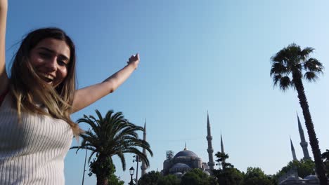 slow motion:beautiful young girl waves turkish flag with view of sultan ahmed or blue mosque in i̇stanbul,turkey,travel concept