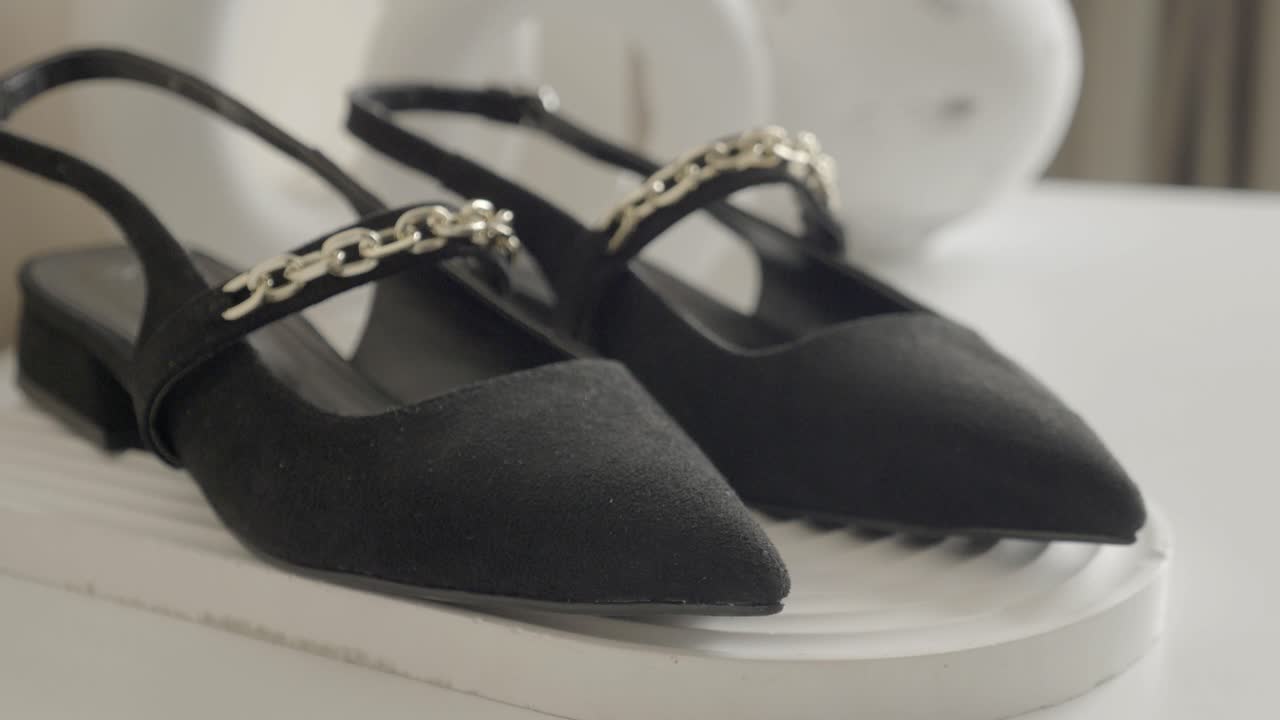 금색 사슬 세부 사항과 함께 검은 suede slingback 신발