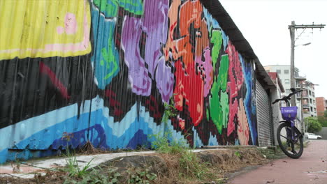 A-bike-for-hire-stands-next-to-a-large-graffiti-mural-in-innerwest-Sydney,-Australia