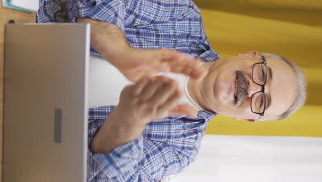 Vertikales-Video-Eines-Alten-Mannes,-Der-Applaudierend-Auf-Den-Laptop-Schaut.