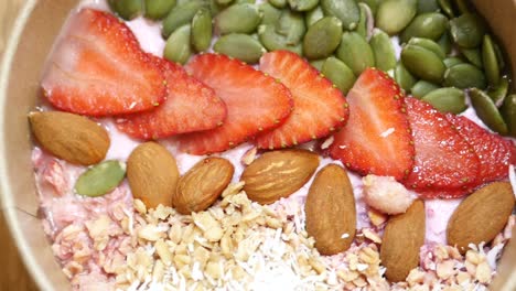 strawberry yogurt granola bowl with almonds and pumpkin seeds