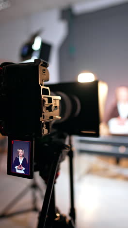 professional camera on tripod with working display. recording a female blogger in the modern photo studio. vertical video.
