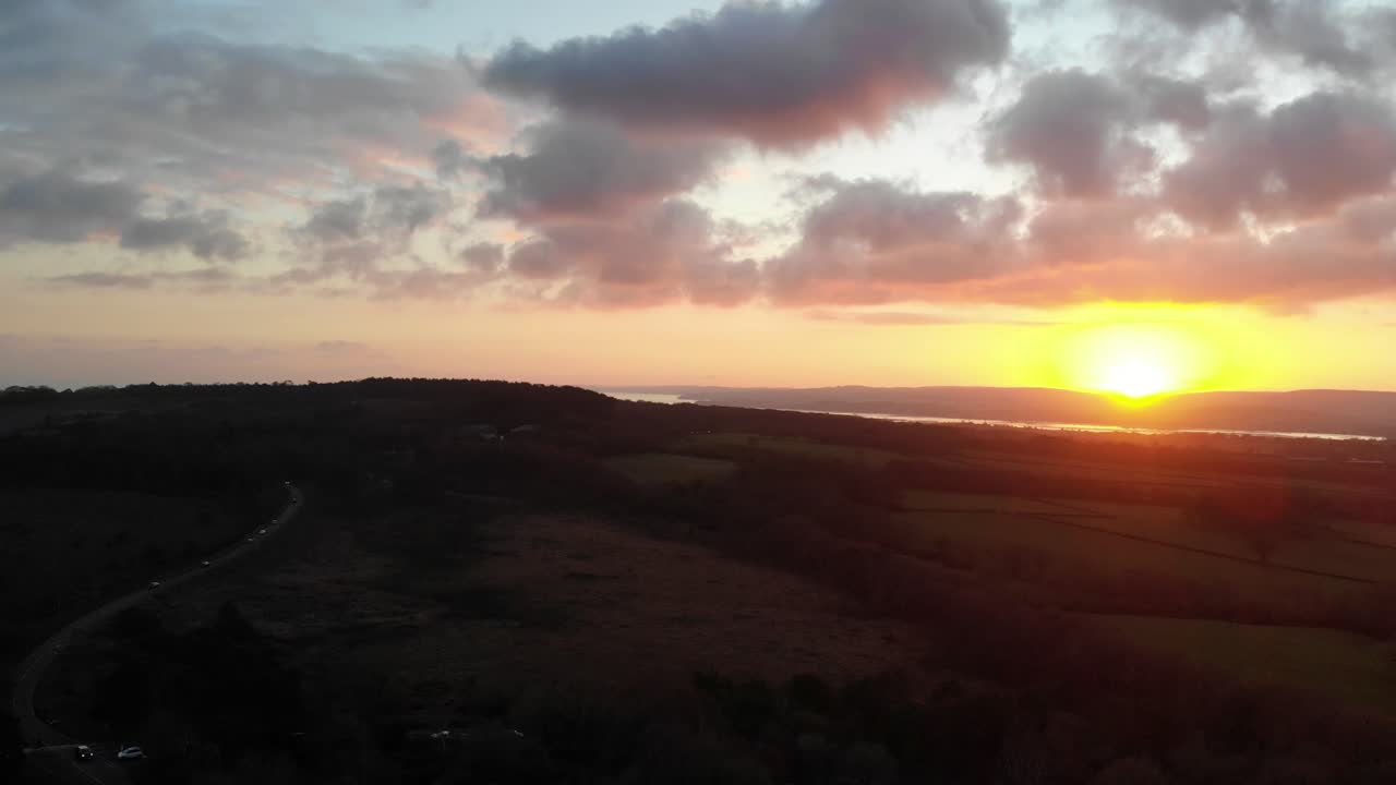 toma aérea mirando hacia exmouth en devon, inglaterra desde woodbury common sobre una calle transitada y con una hermosa puesta de sol dorada