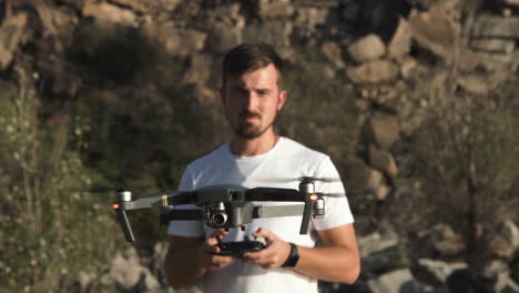 man holding drone in a rocky outdoor setting
