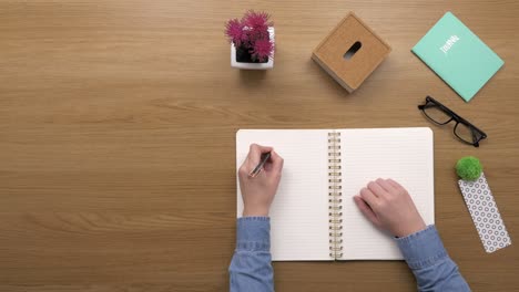 overhead top view of woman writing ideas in diary at desk