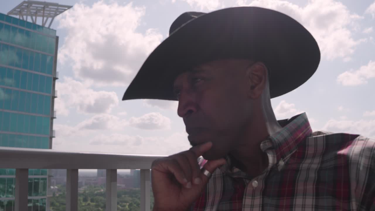 hombre negro con sombrero de vaquero en el balcón en un pensamiento profundo