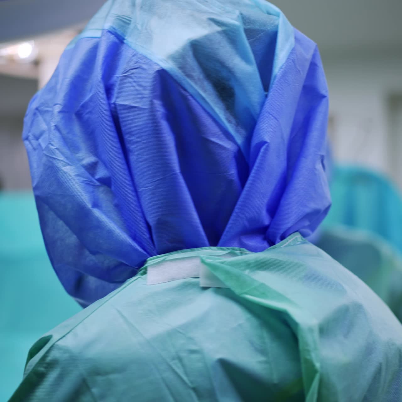 Doctors in protective suits in the modern surgical room. Medics stand under the round lamps over the surgical table