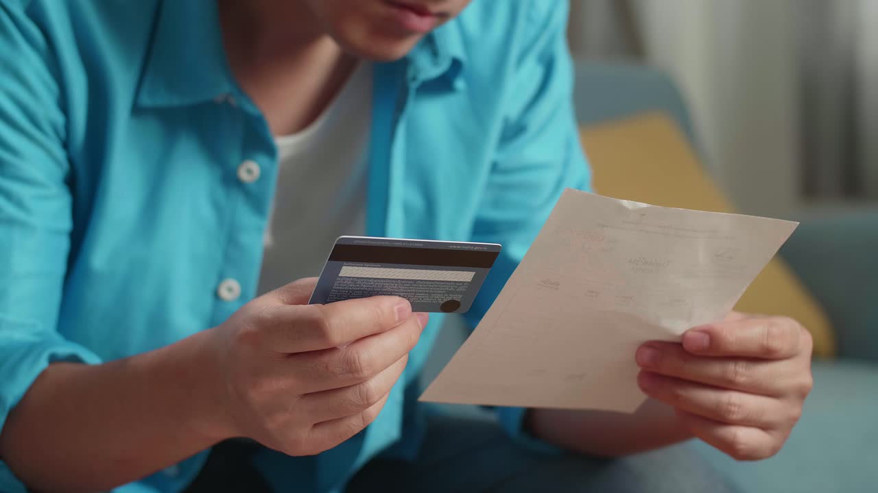 un hombre con una tarjeta de crédito y una factura sacudiendo la cabeza