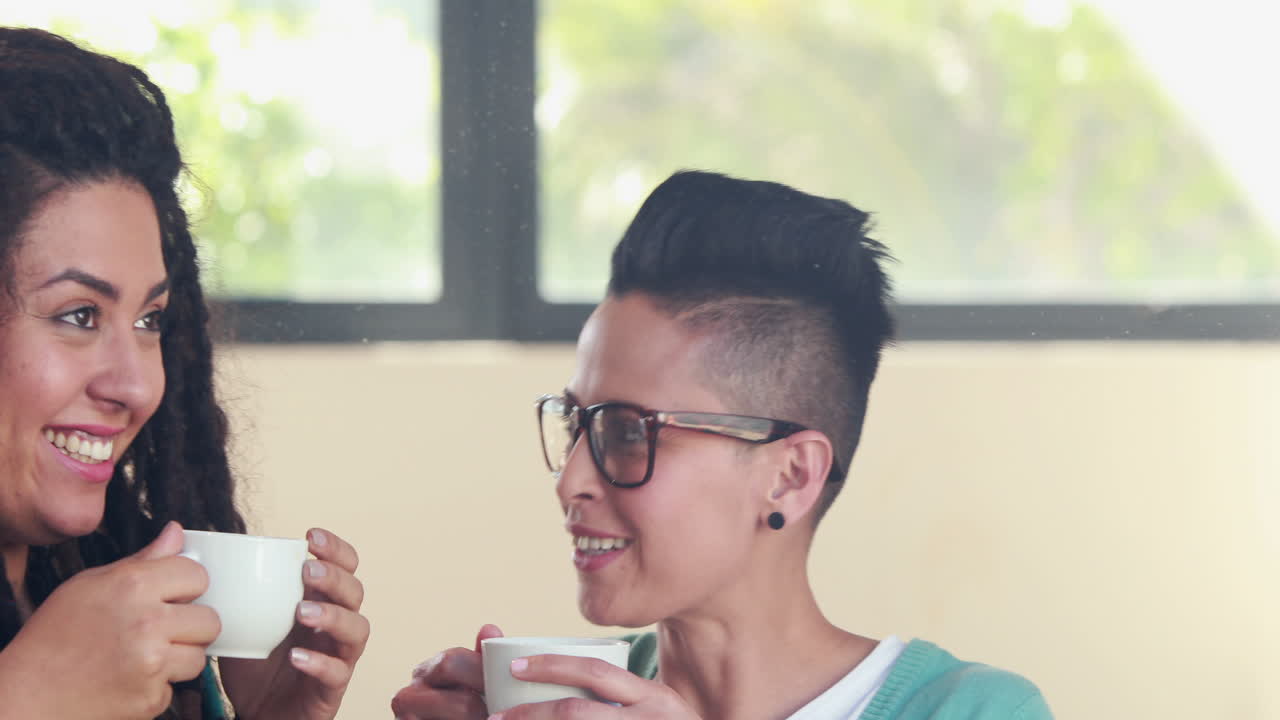 una pareja de lesbianas sonrientes bebiendo café juntos.