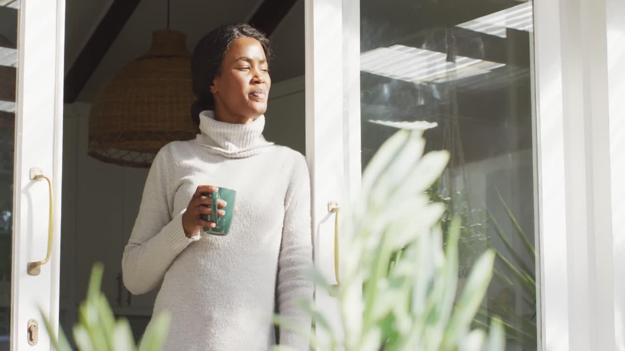 Video di una donna afroamericana felice e rilassata che beve caffè in patio.