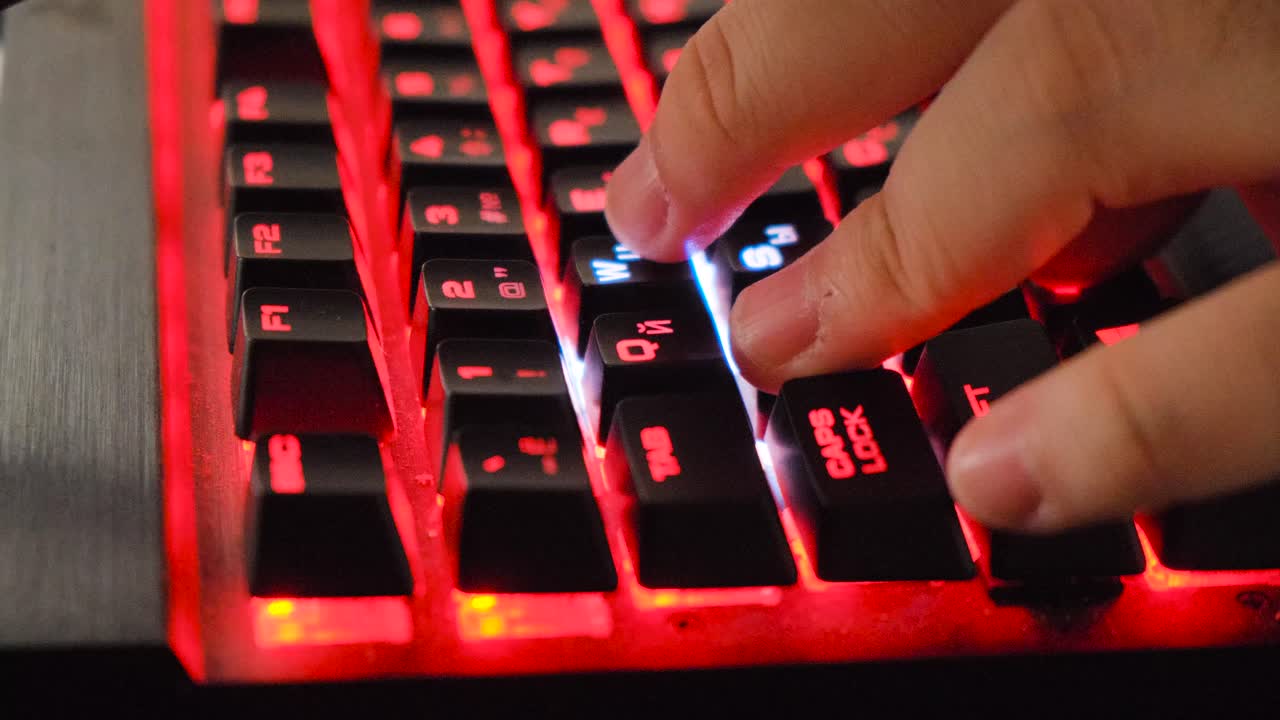 persona escribiendo en un teclado de juego de led rojo