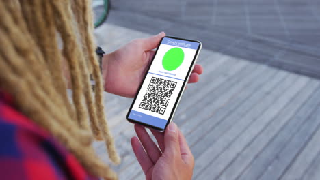 hombre con dreadlocks sosteniendo un teléfono inteligente con certificado de vacunación contra la covid y código qr en la pantalla