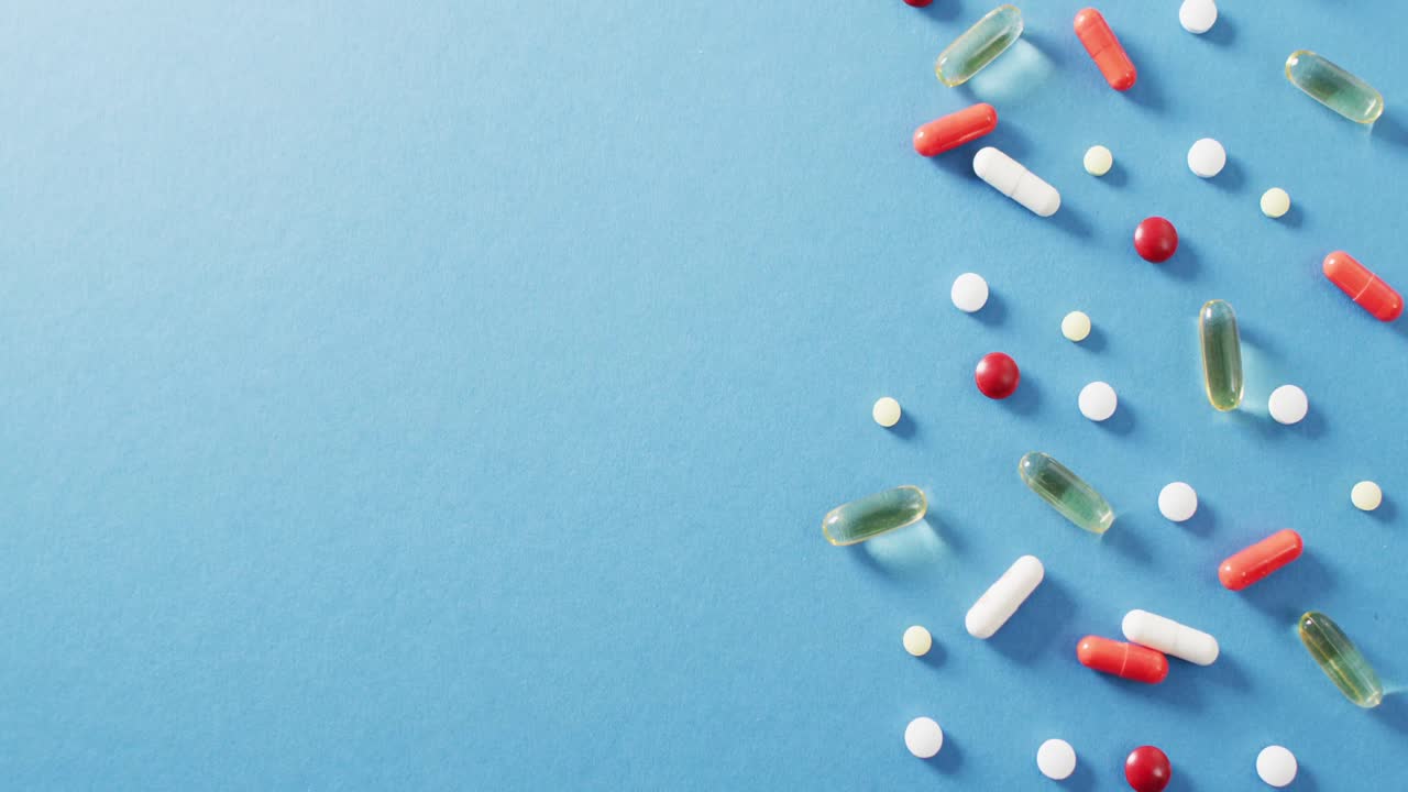 vídeo de una variedad de píldoras y cápsulas sobre fondo azul con espacio para copiar