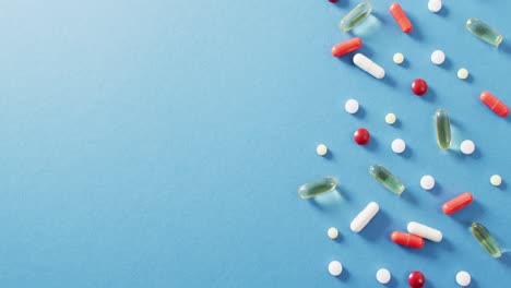 video of a variety of pills and capsules on blue background with copy space