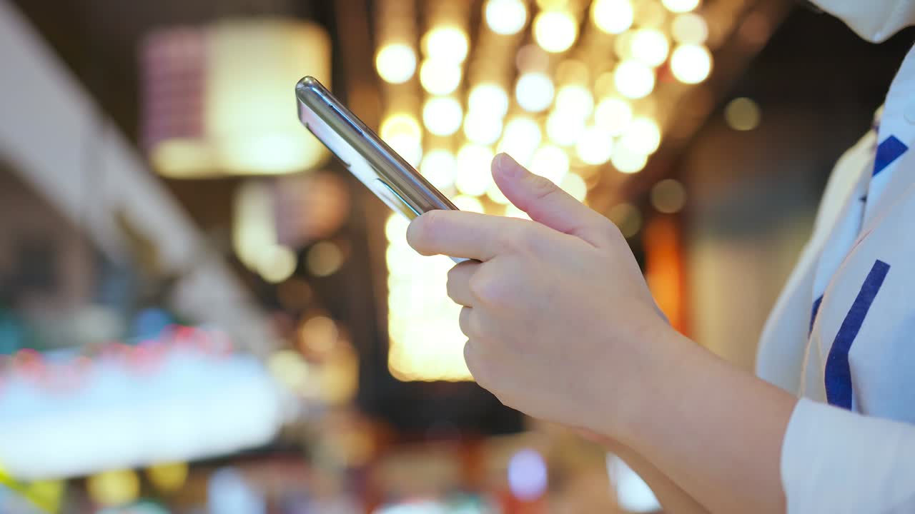 mano femenina de cerca usando comunicación de teléfono inteligente con bokeh ligero de fondo de candelabro