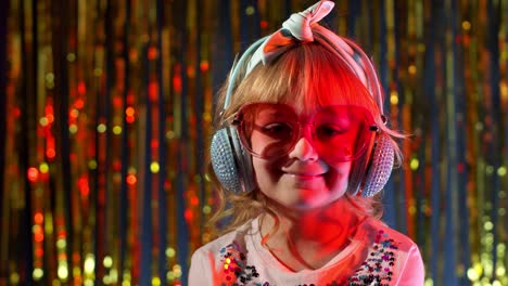 Portrait-of-trendy-stylish-girl-looking-at-camera,-smiling,-child-kid-in-neon-light-at-disco-club