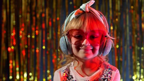 retrato de una chica elegante de moda mirando a la cámara, sonriendo, un niño en la luz de neón en un club de discoteca
