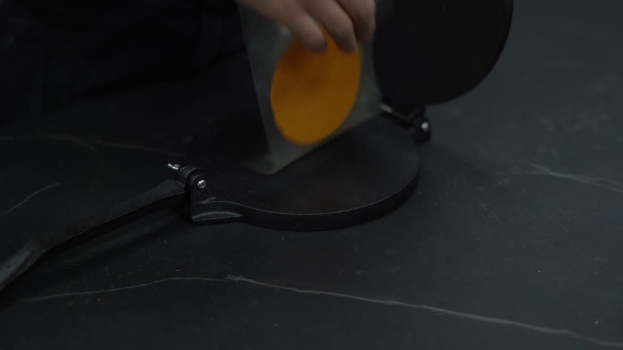 요리사의 손은 반죽을 압축 도구로 은 조각으로 평평하게합니다.