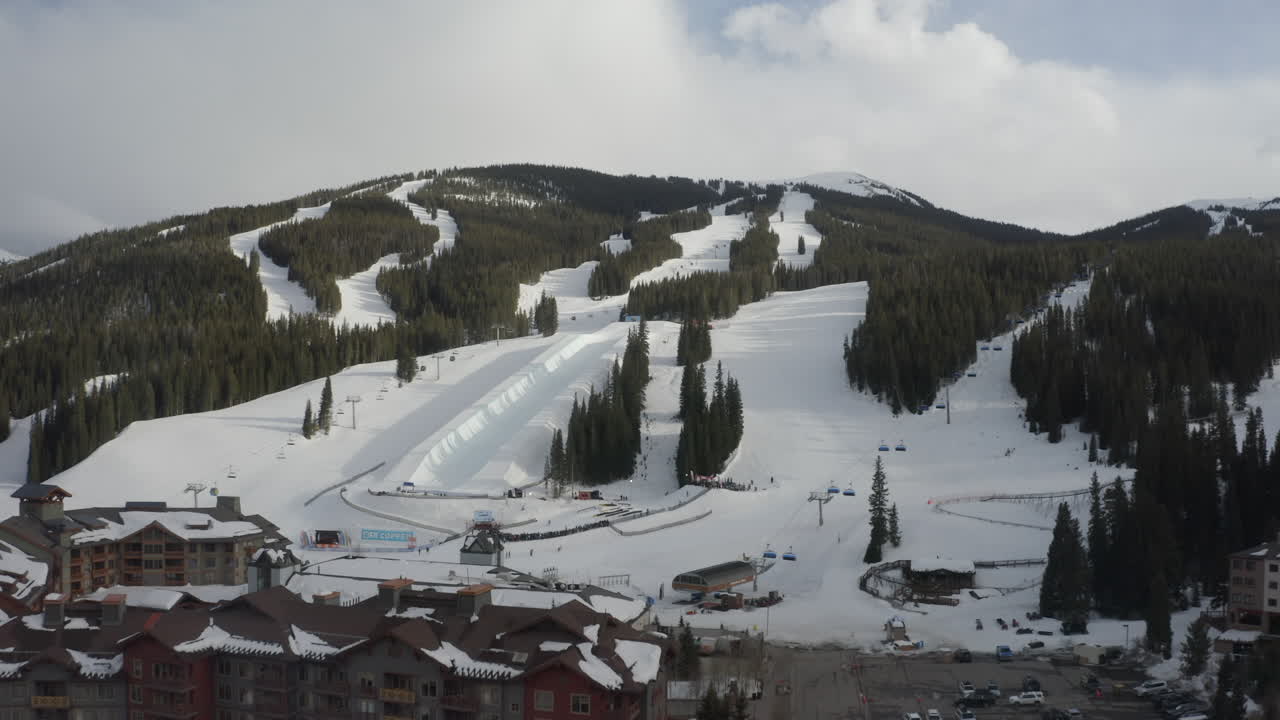 Aerial Drone Copper Mountain Colorado Ikon Epic Pass winter spring cloudy snowy afternoon sunset last light half pipe Flyer chairlift ski runs center village cinematic slowly reveal forward motion