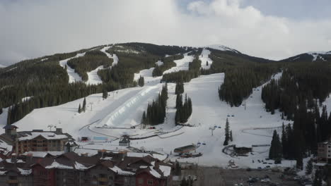 aerial drone copper mountain colorado ikon epic pass winter spring cloudy snowy afternoon sunset last light half pipe flyer chairlift ski runs center village cinematic slowly reveal forward motion