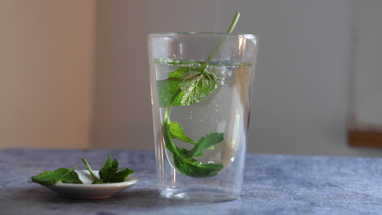 Video di acqua calda versata in una tazza per preparare il tè alla menta