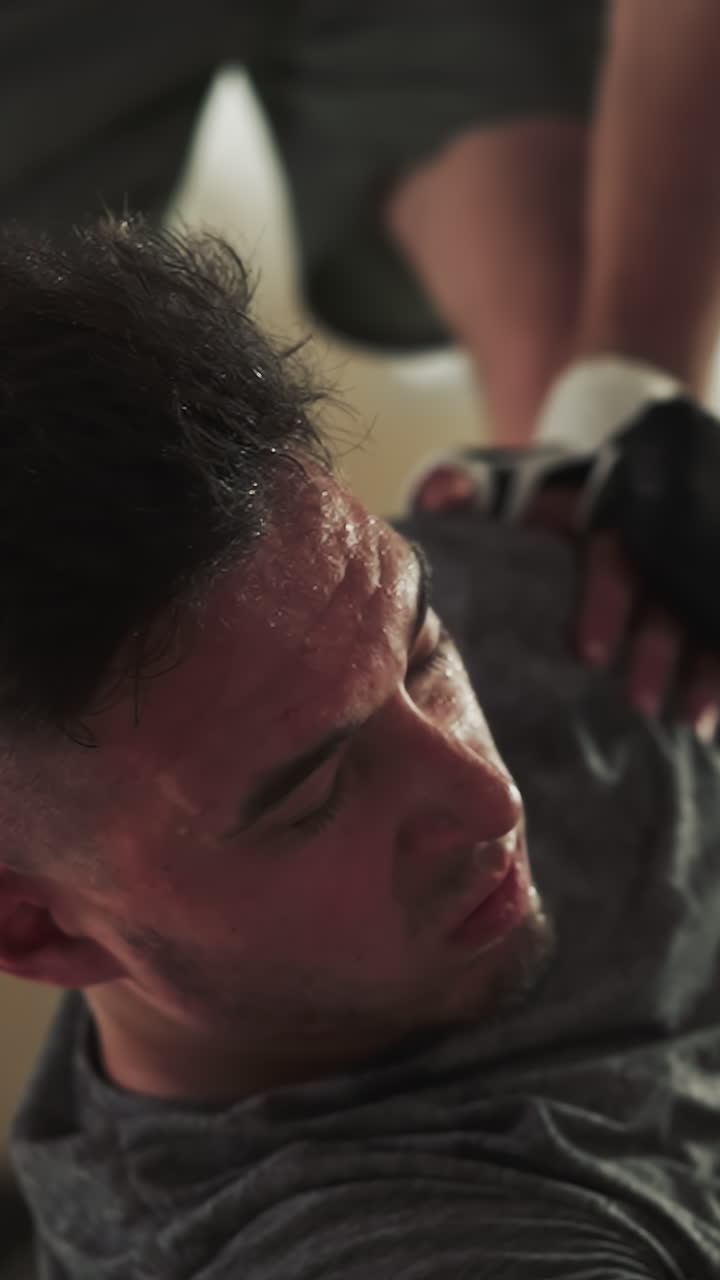 무방비한 남자가 스포츠 클럽에서 무거운 주먹에 쓰러져 있습니다. 쓰러진 싸움은 체육관 바닥에서 취약한 머리에 부히고 슬로우 모션으로 고통받습니다.