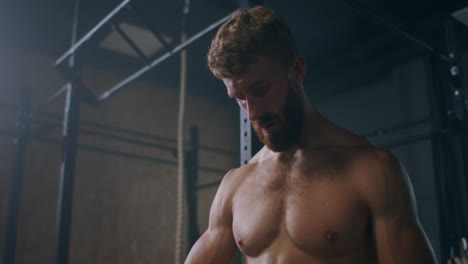 joven atlético caucásico cambiando poniendo correas de levantamiento de pesas en el vestuario del gimnasio antes del entrenamiento cámara lenta. ata los brazos a la barra con correas de fitness.