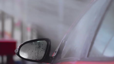 car wash: spraying water jet on red car side window