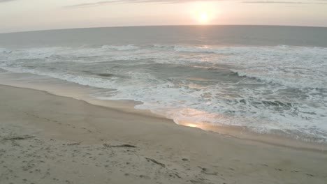 a tilt reveal of the sunset with the beach as the first view