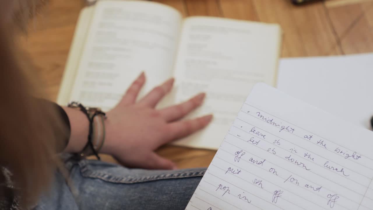 fotografía de diapositivas de un cuaderno blanco con algunas notas, libros con mano femenina en el fondo