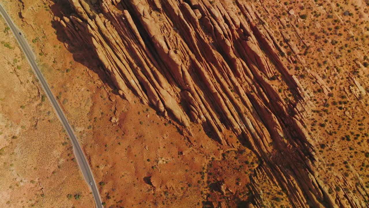 Stunning rocks of American canyons on sunny daytime. Highway road passing through the dry desert in Utah State from top view.