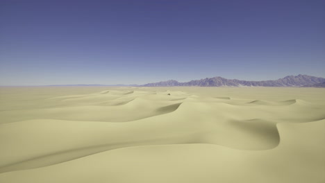 vast yellow sand dunes stretch under a clear blue sky in a desert landscape