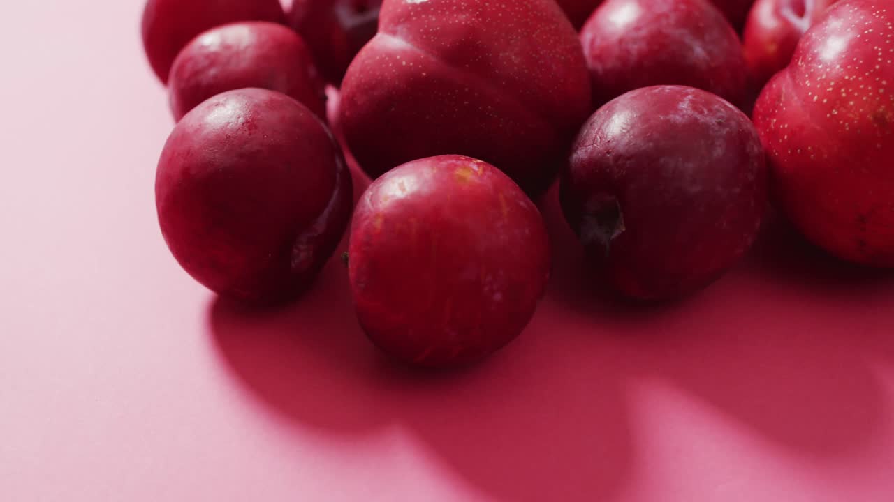 Video of fresh plums lying on pink surface