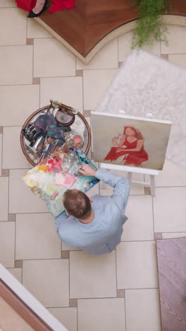 el pintor mezcla pigmentos en la paleta en el caballete. el artista combina diferentes tonos para representar detalles de retratos de mujeres en un apartamento de lujo. ocupación artística