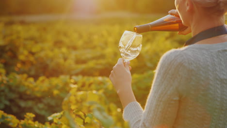 woman pours white wine into a glass private tasting at the winery