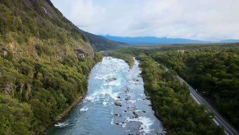 aerial view truck left of petrohue river with mountains on the side, cloudy mountains in the background, southern chile