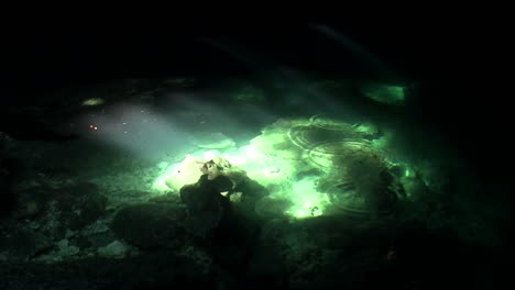 piscinas verdes brillan a la luz del sol en el fondo de una cueva