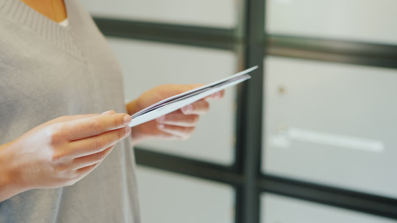 una mujer mira las letras, solo se ven las manos en el marco contra el fondo de los buzones