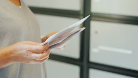 Eine-Frau-Sieht-Sich-Die-Buchstaben-An,-Nur-Die-Hände-Sind-Im-Rahmen-Vor-Dem-Hintergrund-Von-Briefkästen-Sichtbar