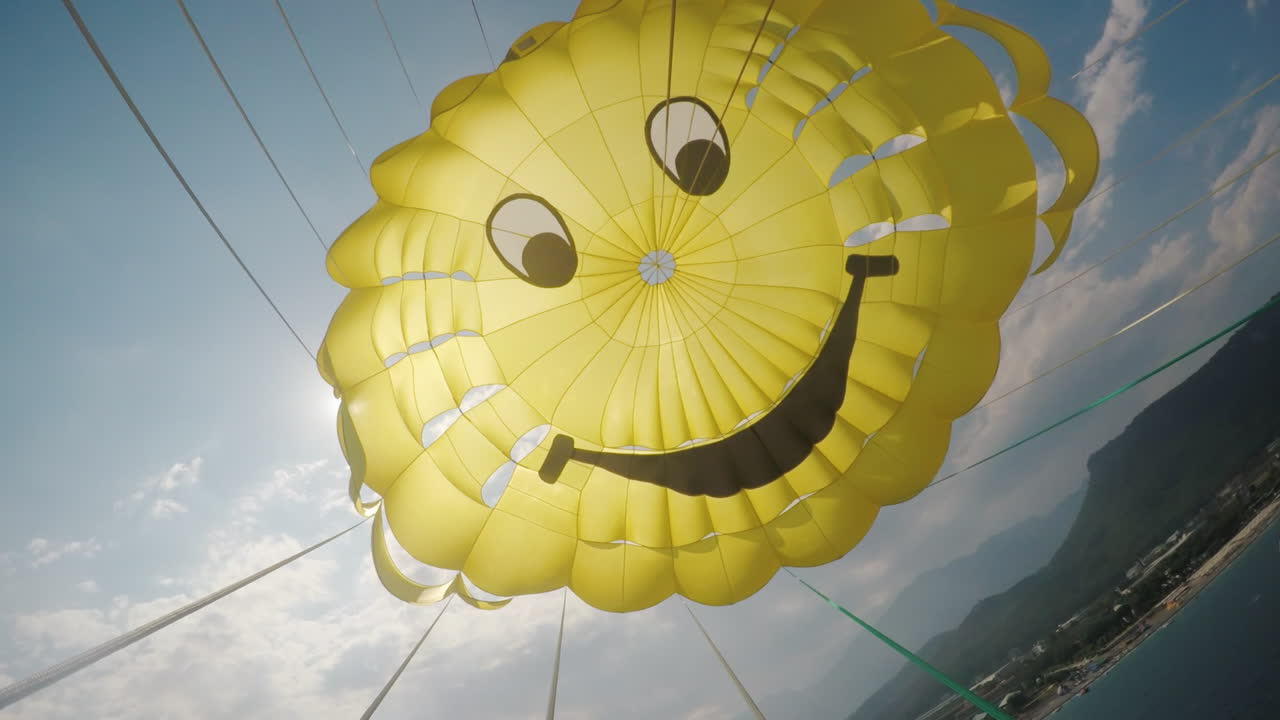 푸른 하늘과 그것을 통해 찌르는 태양에 대한 낙하산의 시원한 노란색 돔