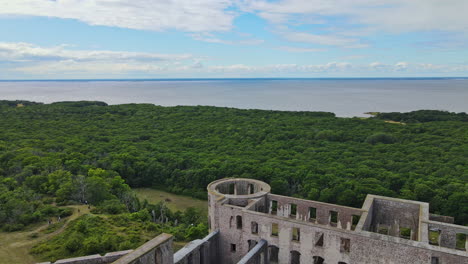 Drones-Volando-Sobre-Las-Ruinas-Del-Antiguo-Castillo-De-Borgholm-En-Oland,-Suecia-Con-Frondosos-árboles-En-La-Costa-Del-Mar-Báltico---Antena