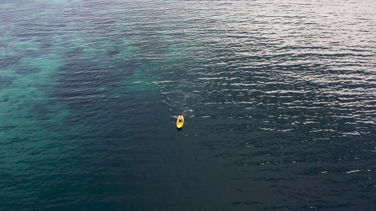 Young Man On Canoe Rowing At Blue Sea With Calm Waves