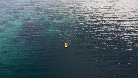 young man on canoe rowing at blue sea with calm waves