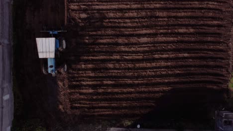 overhead shot of blue tractor cultivating soil of agriculture land, machachi, ecuador