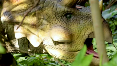 a triceratops animatronic moves its head in a dense, sunlit forest environment, creating a lifelike prehistoric scene