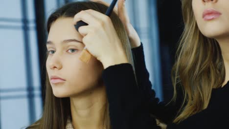 el maquillador hace el maquillaje de una mujer joven en el estudio 2