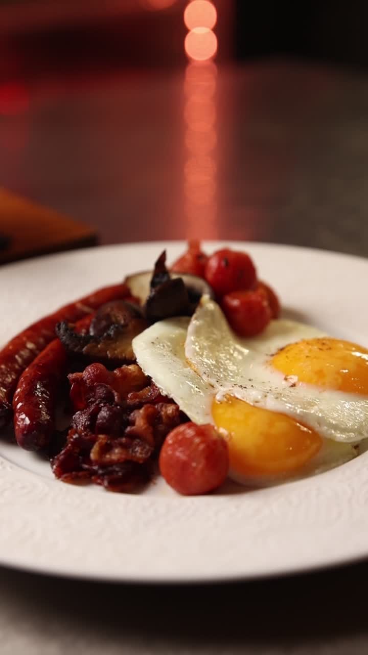 Piatto gourmet per la colazione con uova fritte, salsiccia, pancetta e pomodori