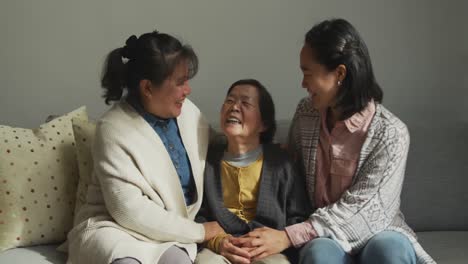 Smiling-senior-asian-woman-with-two-adult-daughter-and-granddaughter-embracing