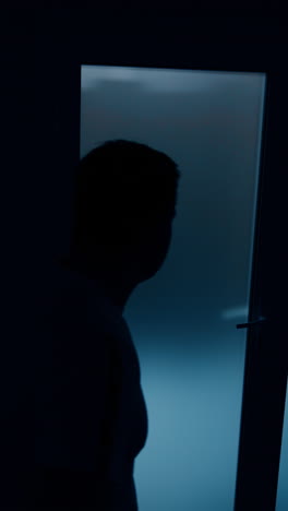 dark male silhouette walking near the door in hospital. husband is nervous for the wife giving birth to a baby. vertical video